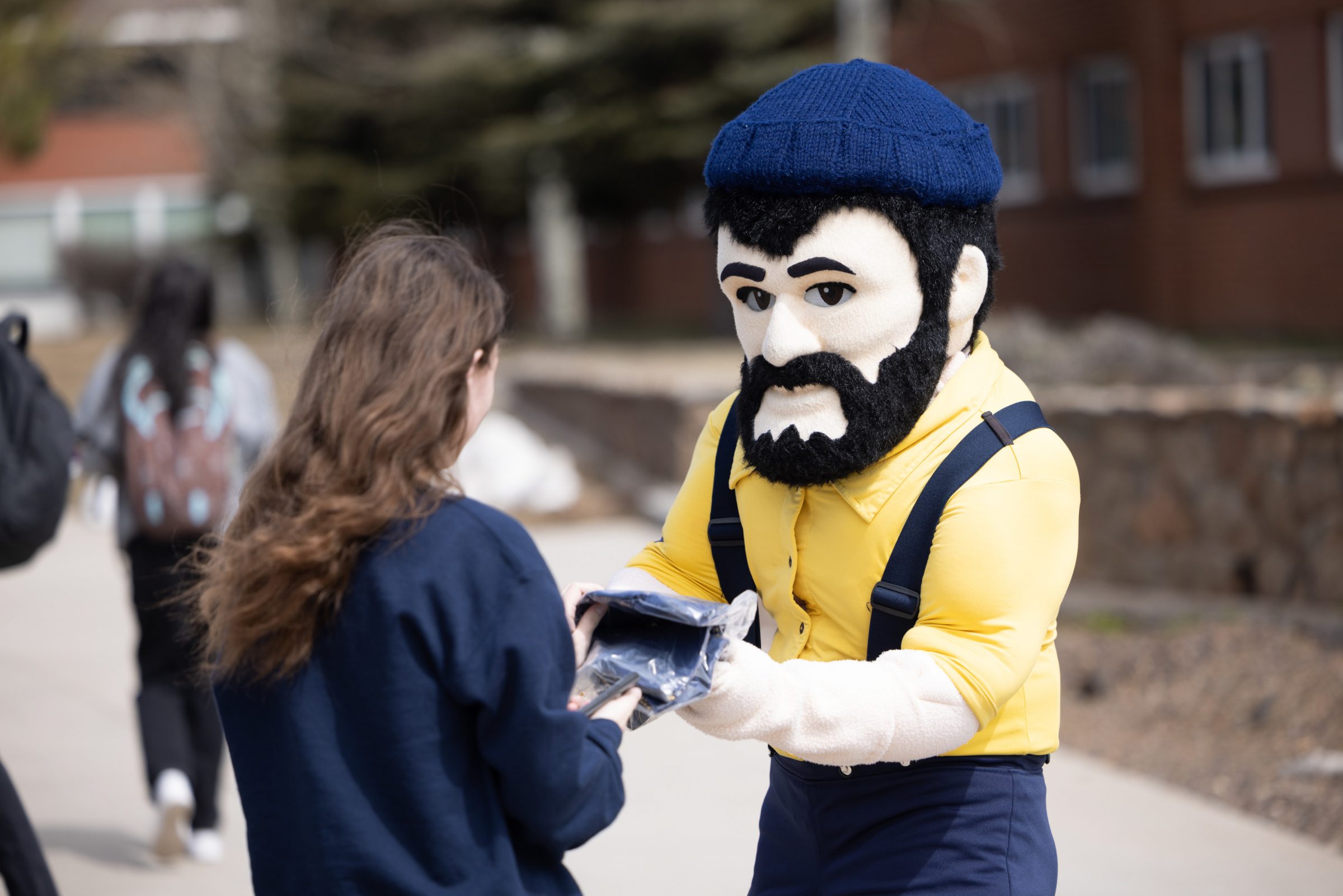 N A U Louie handing student swag out on Giving Day.