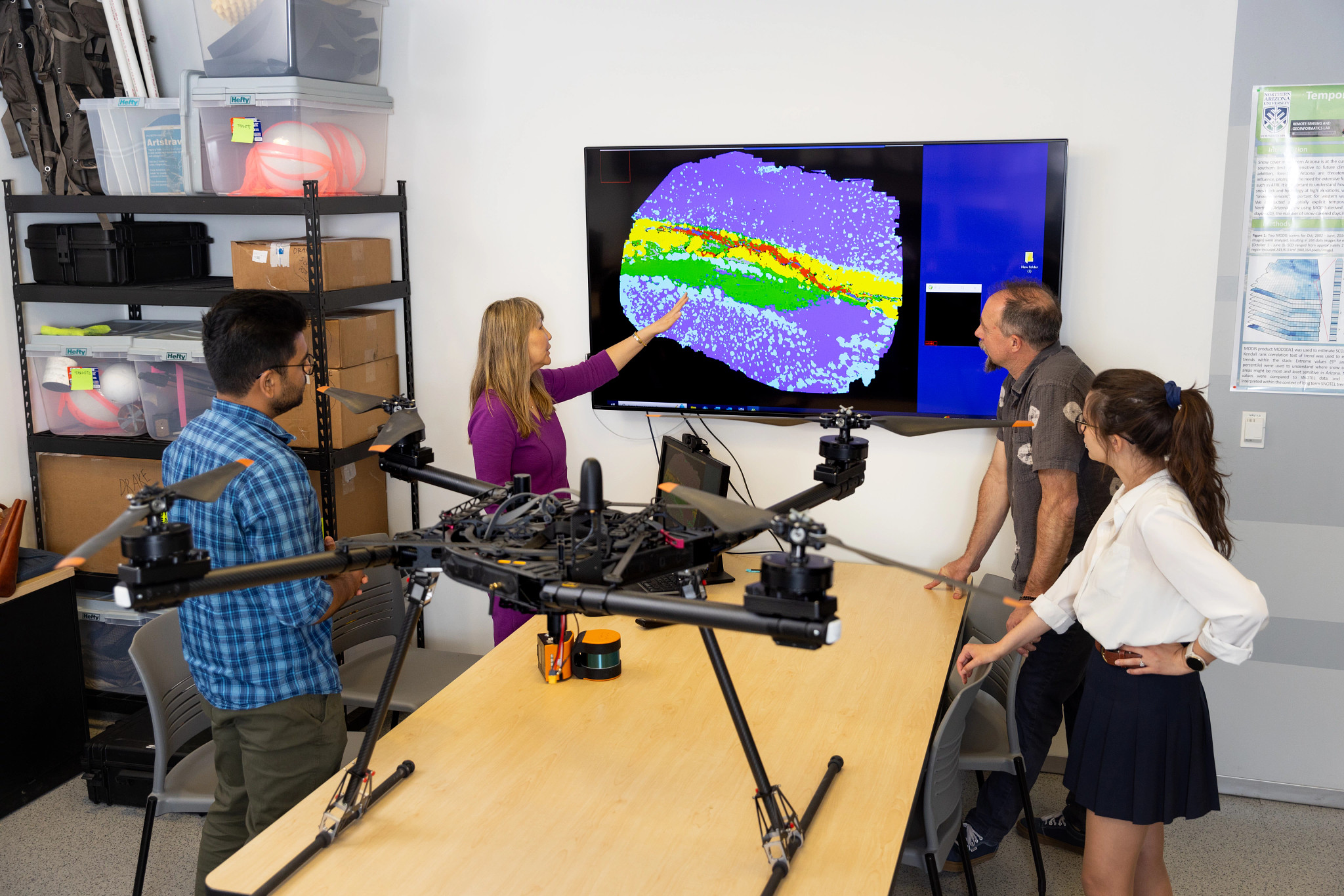 Students and professors analyzing a thermal map taken by a large drone.