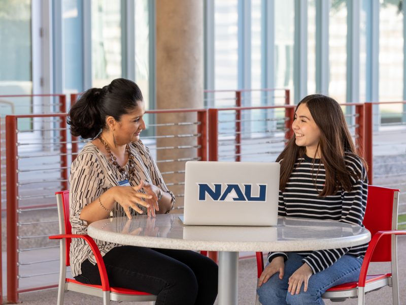 Advisor talking with her student in front of an N A U laptop.