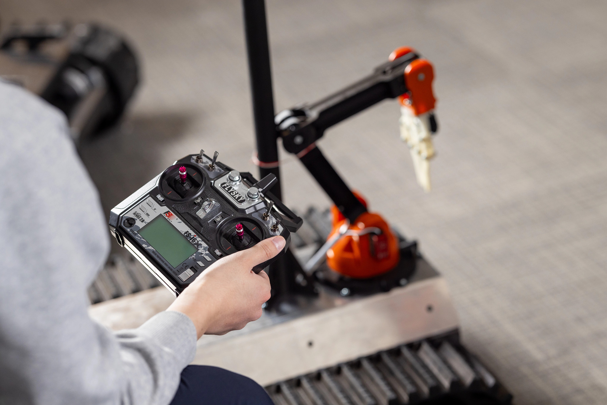 Mechanical engineering student using a remote controller to operate a mechanical arm.