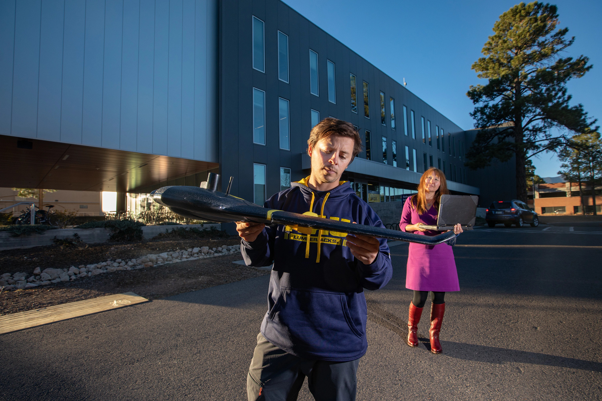 Professor and student preparing to launch a remote-controlled plane outside.