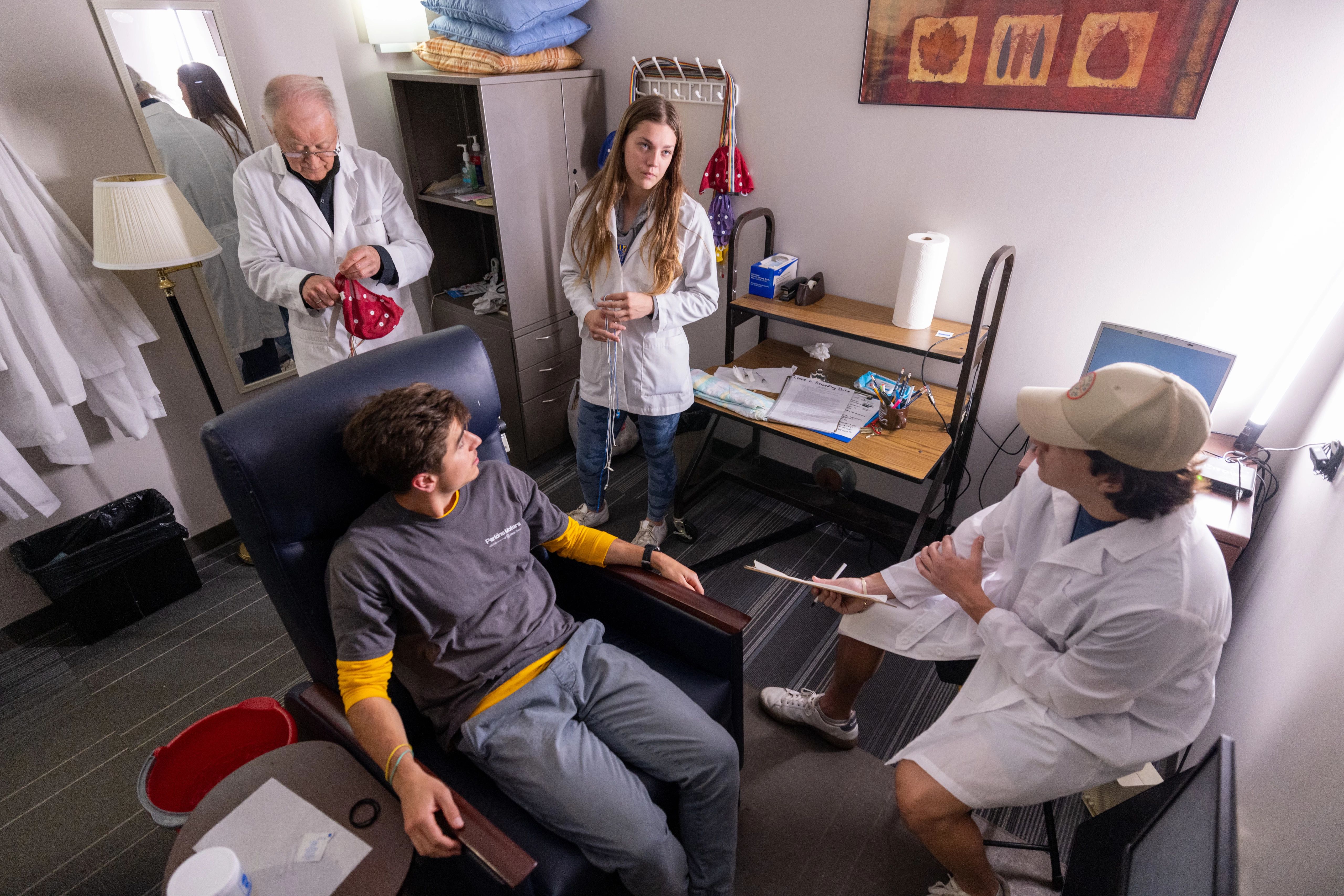 Students and staff working with patient in psychology lab.