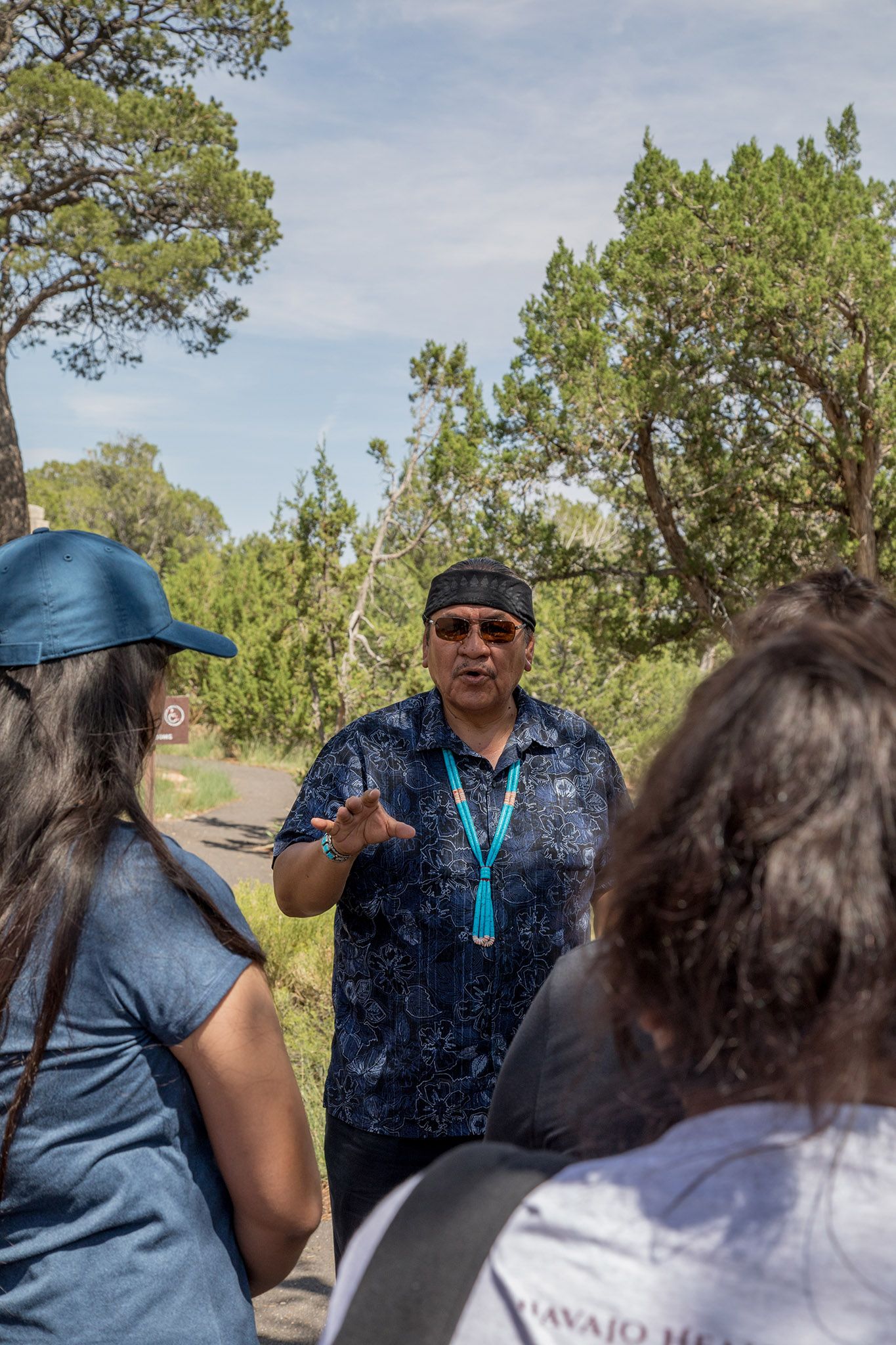 Native American man talking to students in the forest.