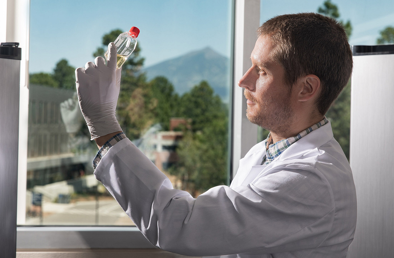 Jason Ladner holding a bottle of liquid in the Pathogen and Microbiome lab.