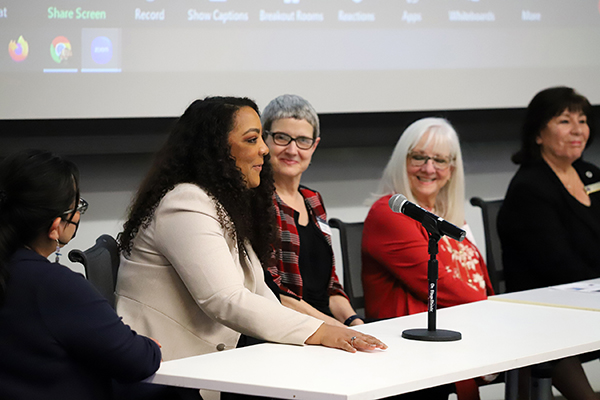 Three female workshop speakers talking to workshop attendees.