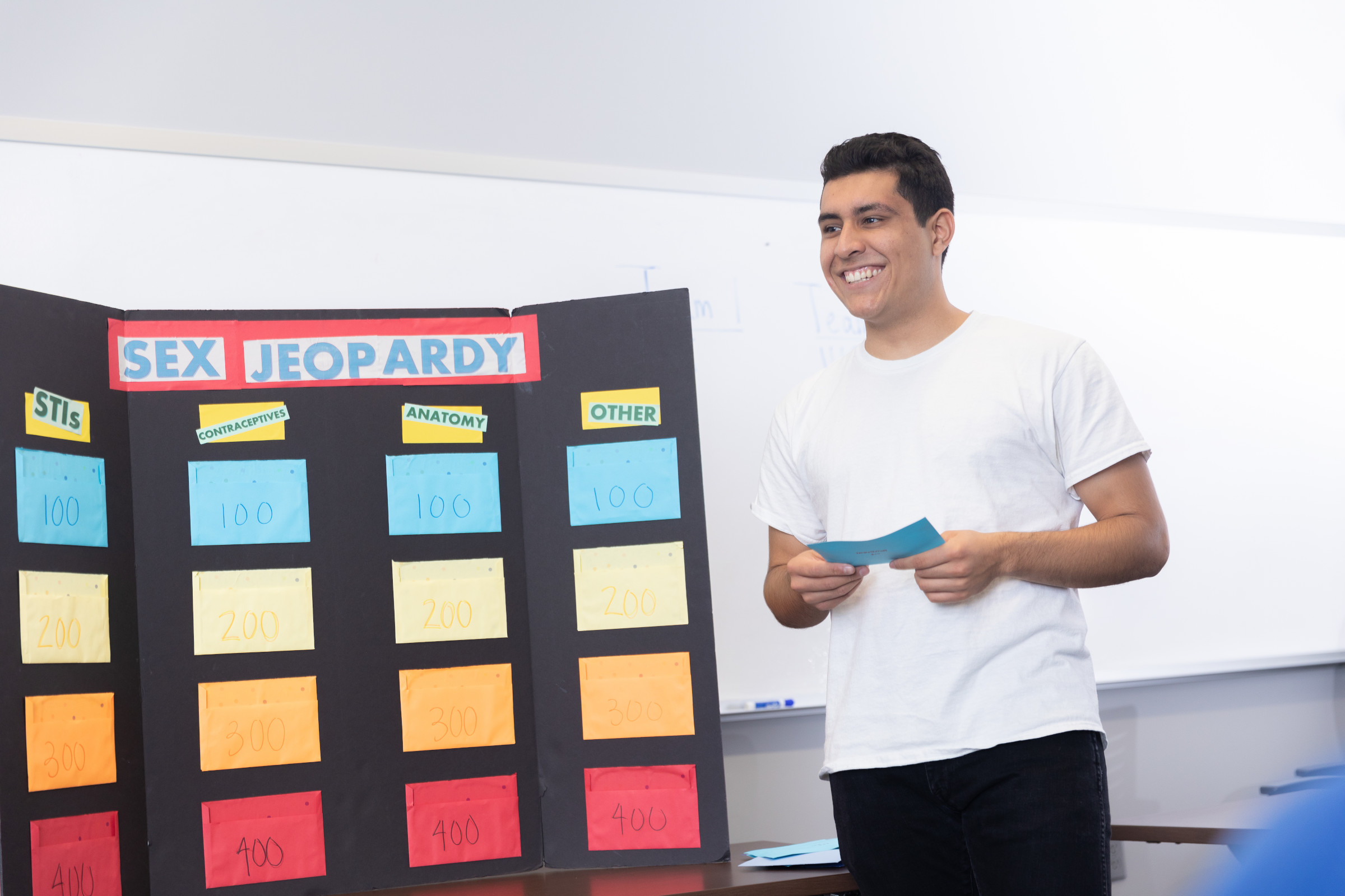 A guy standing in front of a game call "sex jeopardy."