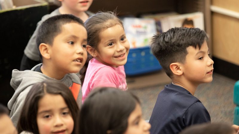 Group of children smiling in a classroom.