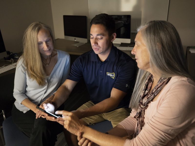 Two researchers talking to a student in an office.