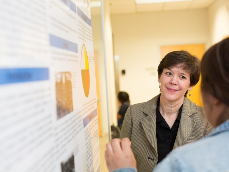 Julie Baldwin smiling next to research poster.