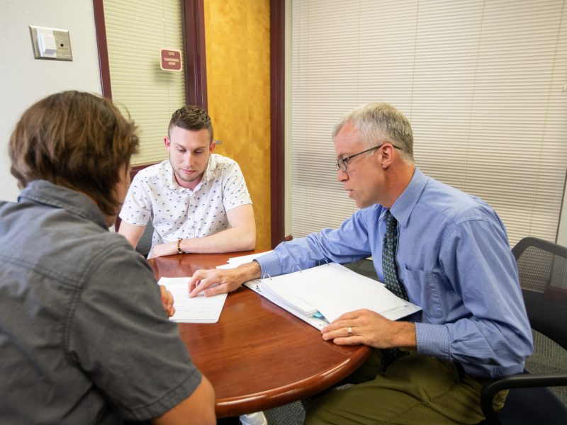 Person showing information to students at a table.