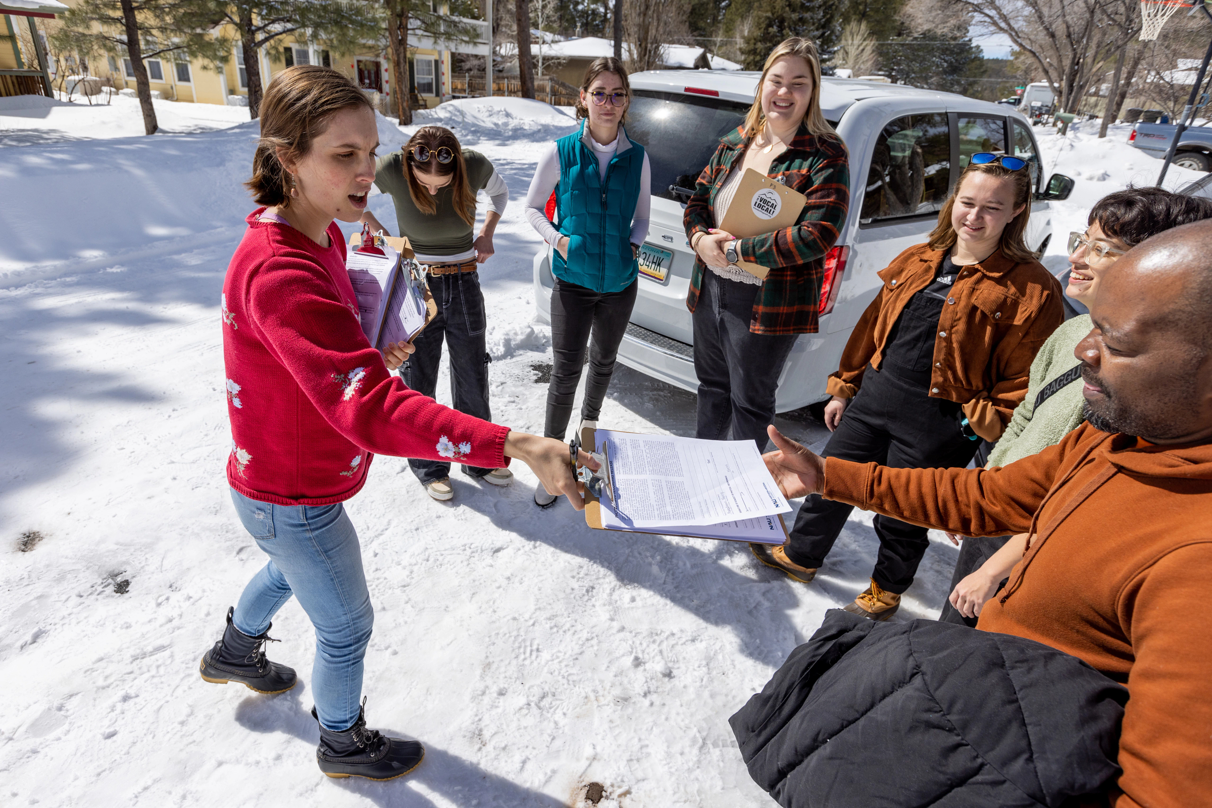 Group of people standing in the snow handing out community surveys.