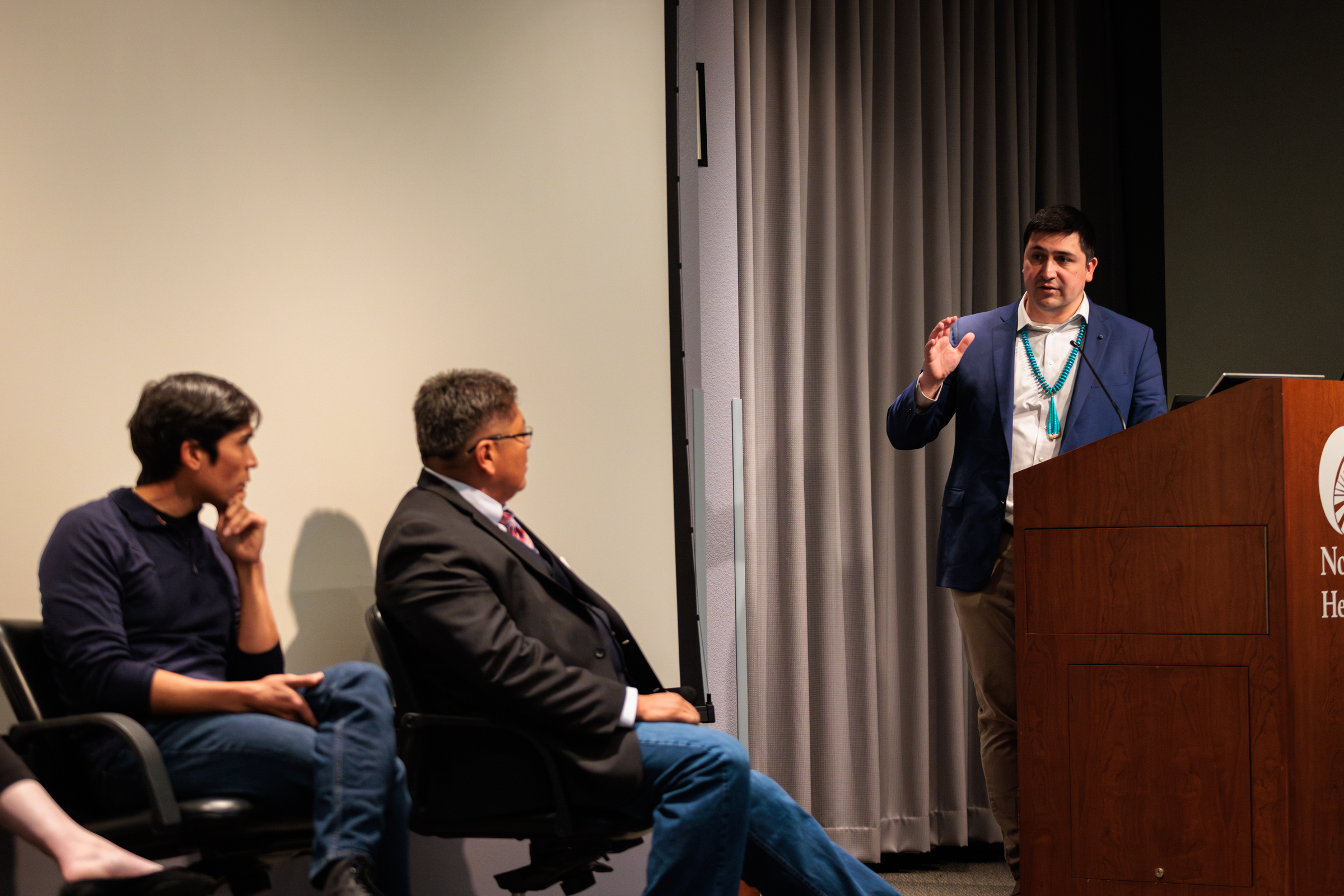 Michael Charles, Jonathan Credo, Sarah Roach, and Tommy Rock sititng and standing near podium.