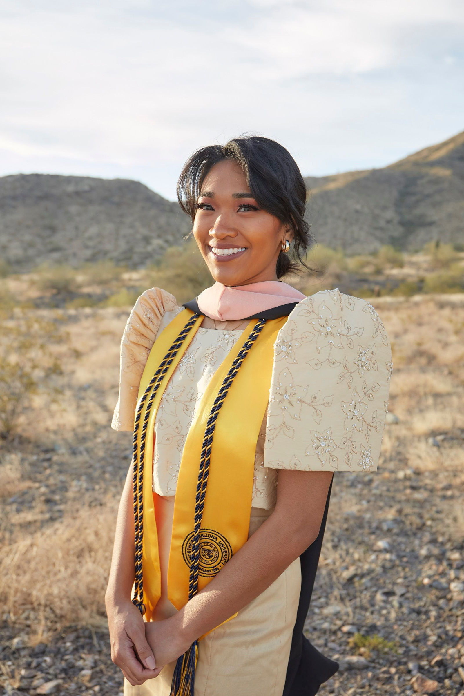 Ashley Lazaro wearing a dress and graduation stole and academic cords.