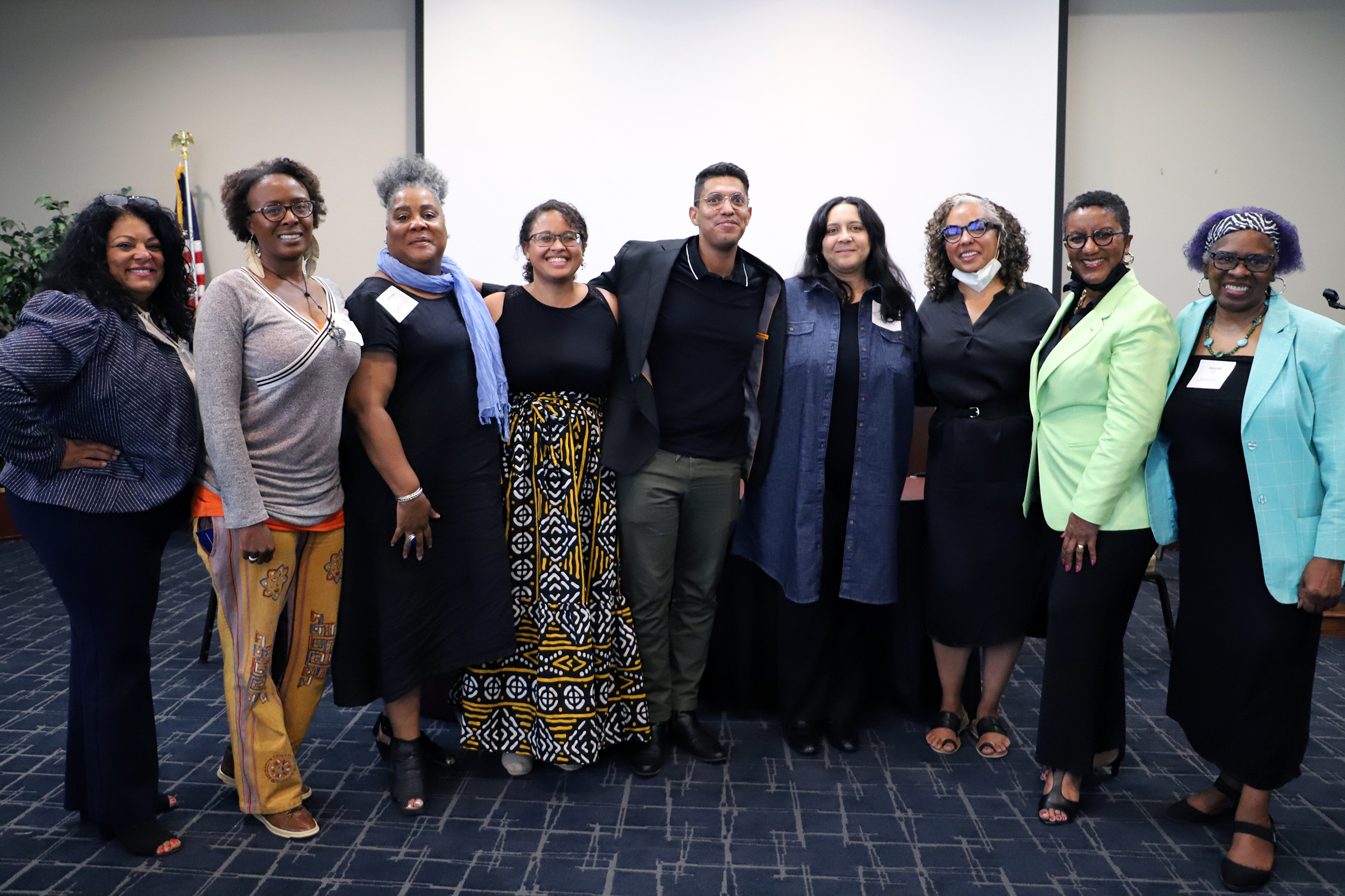 Participants stand together in fornt of projection screen at Black Lived Exerpience conference event. 