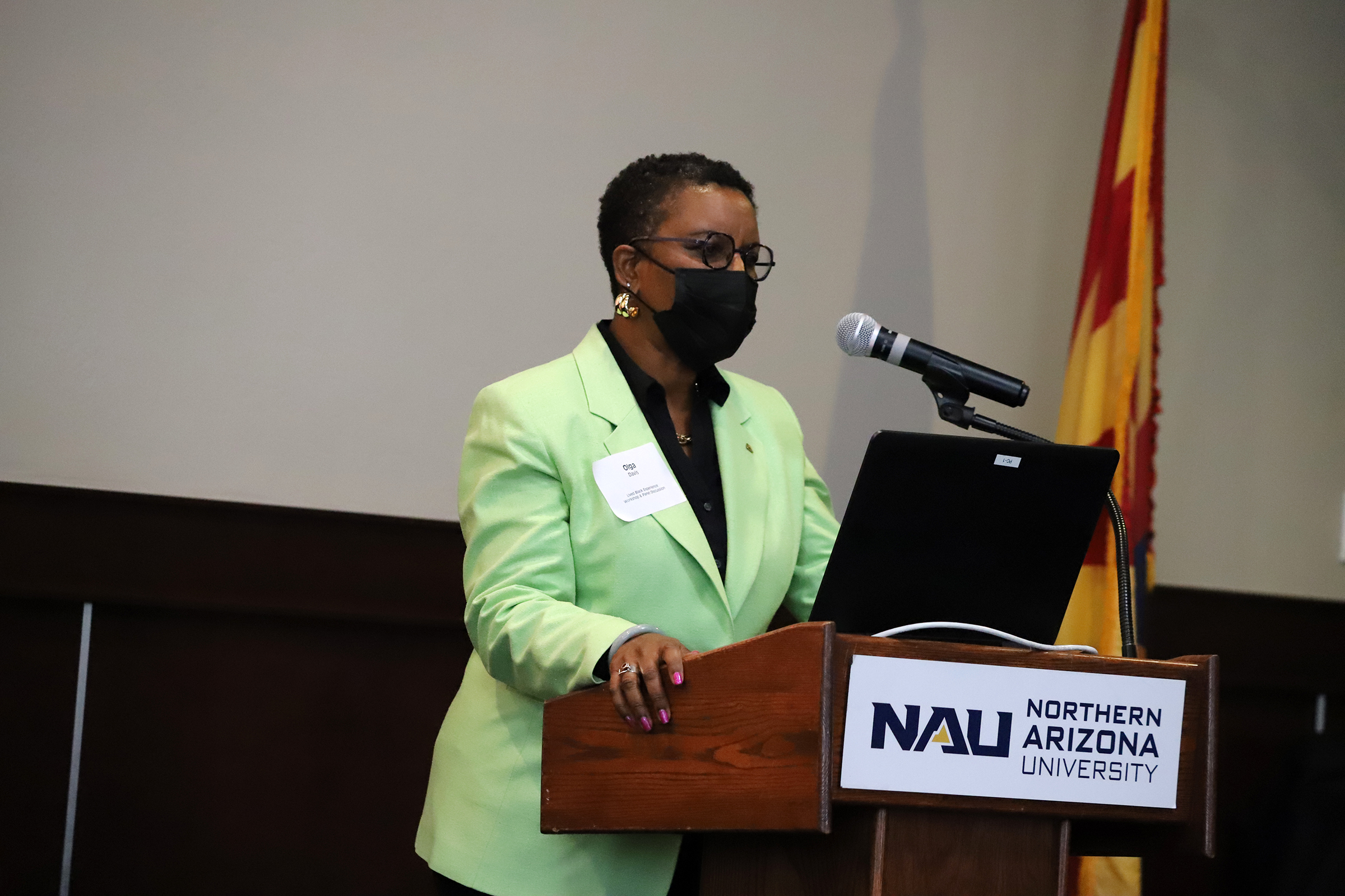 Speaker in green suit at a podium.