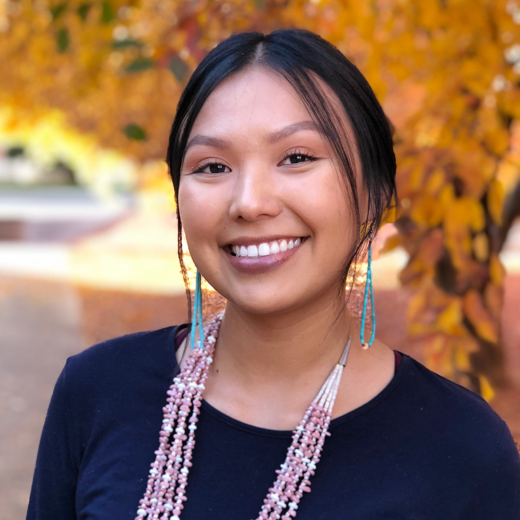 Chassity Begay is wearing a black shirt and wearing Native American jewelry.