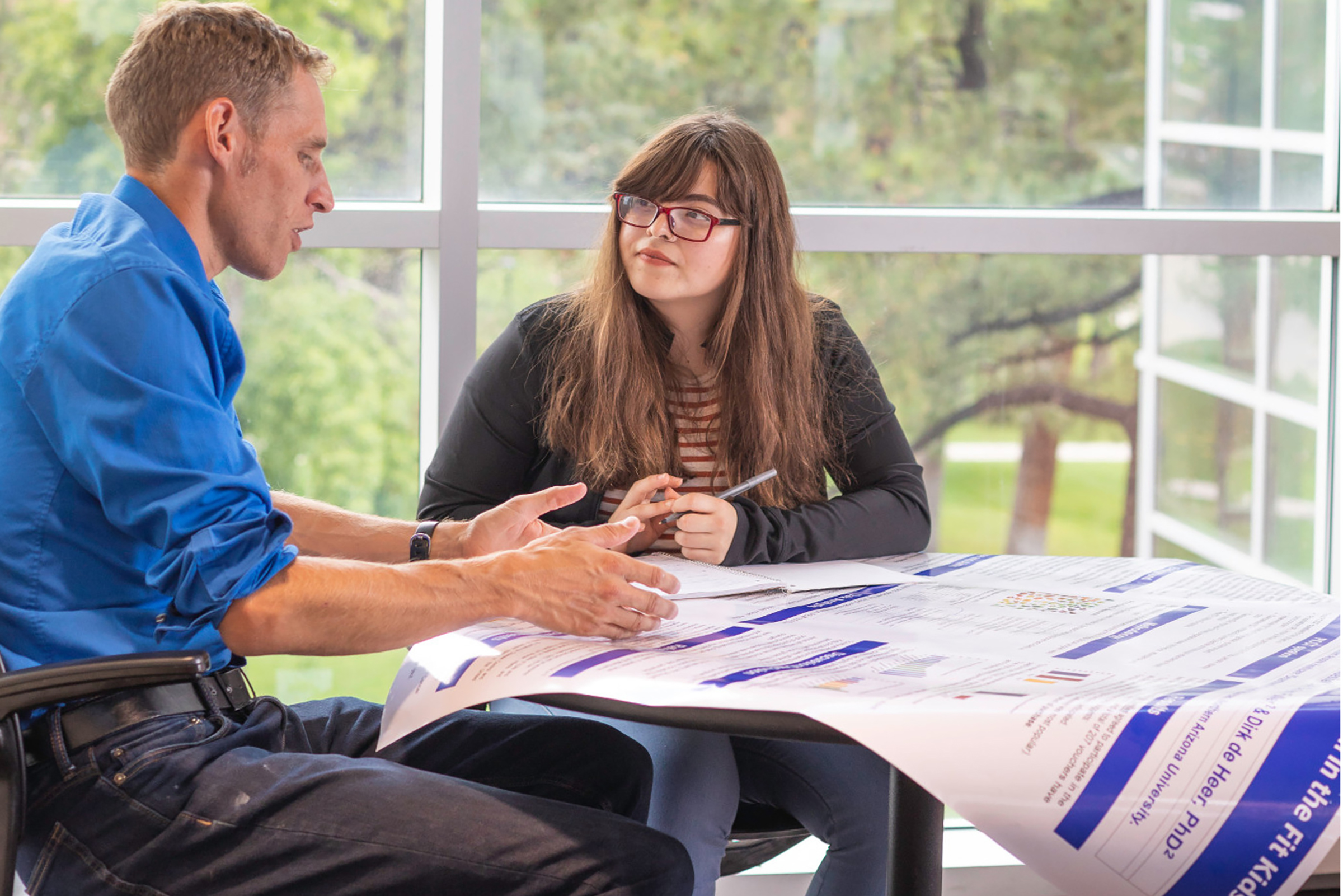 Dirk de Heer talking to a student at a table.