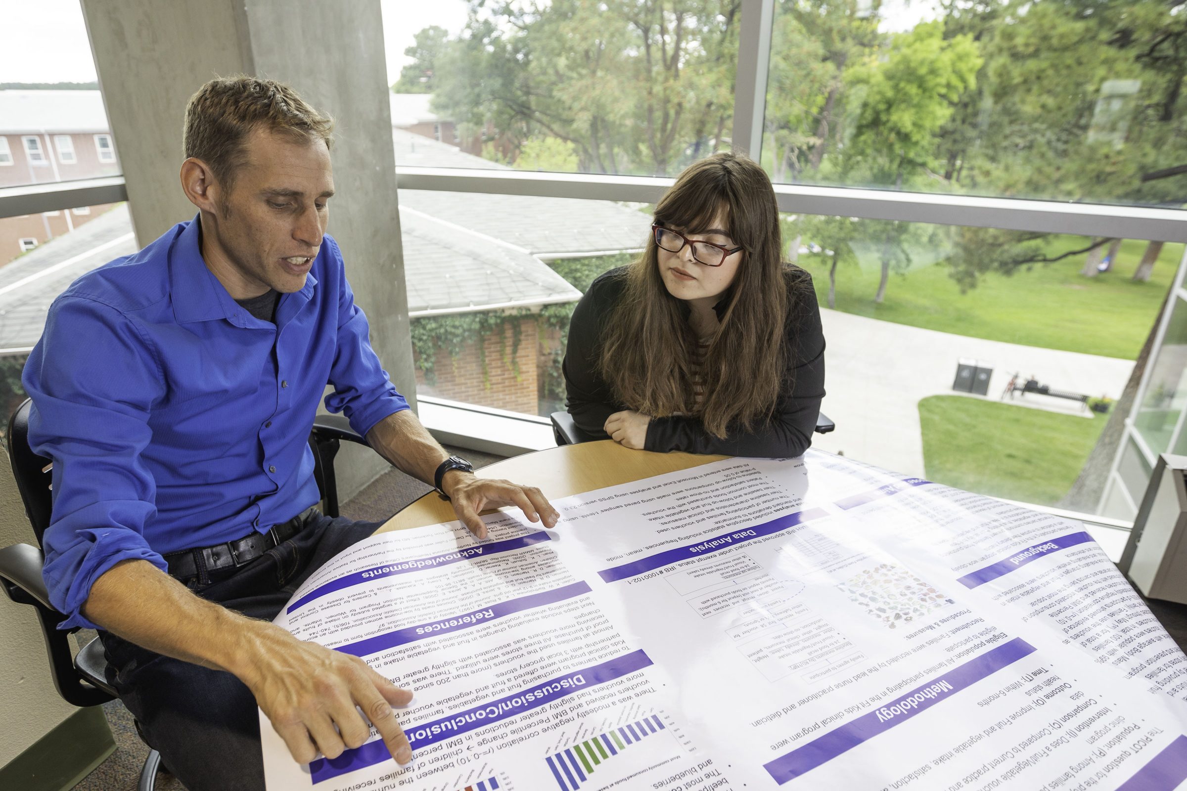 Dirk de Heer showing a student a research poster.