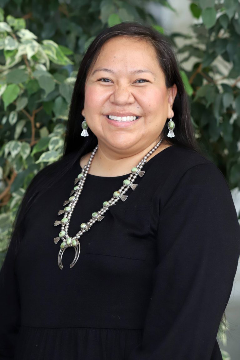 Janet Yellowhair smiles wearing traditional necklace and earrings.