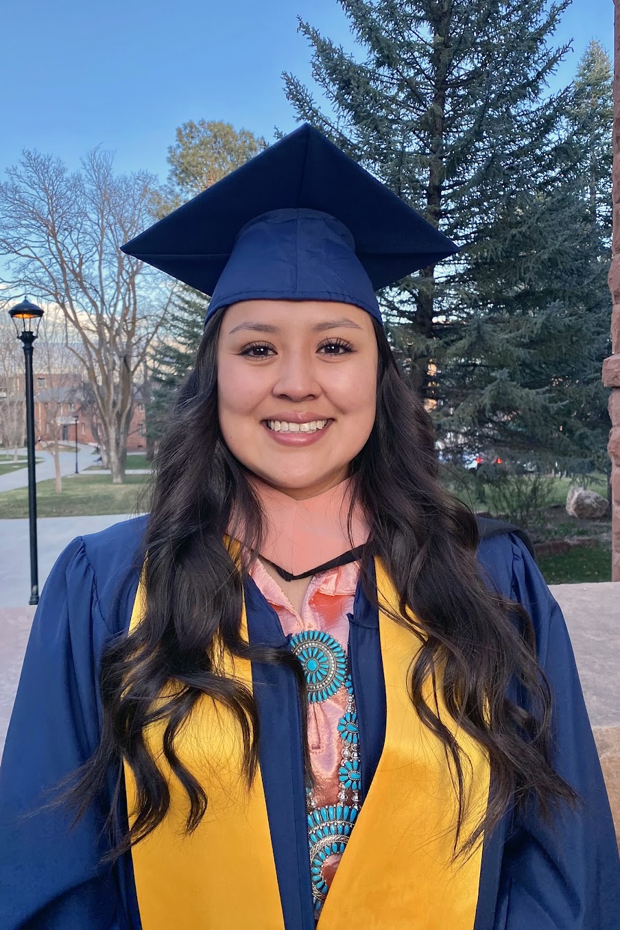 Jennifer Ashleigh Hudson in graduate attire posing outside.