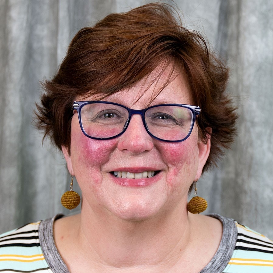 Nancy Jones, PhD, MA portrait wearing a a multiple colored, striped shirt.