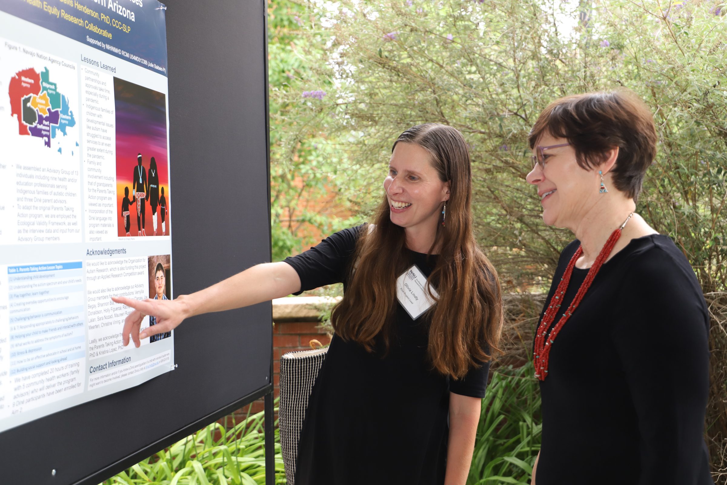 Olivia Lindly and Julie Baldwin looking at a research poster.