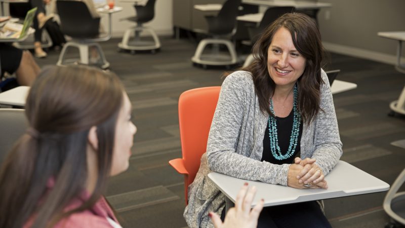 Samantha Sabo talking to a student in a classroom.