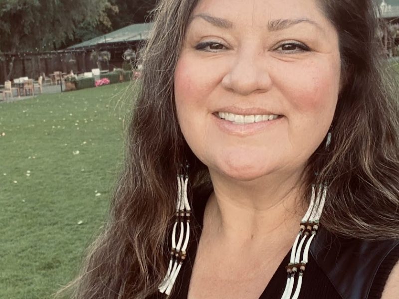 Winona Reid wearing beaded earrings outside in the forest.