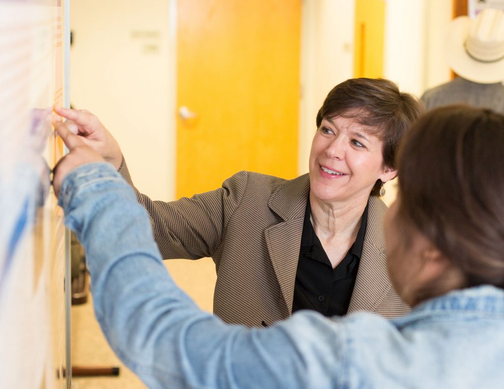 Julie Baldwin and student pointing to an item on a research poster.