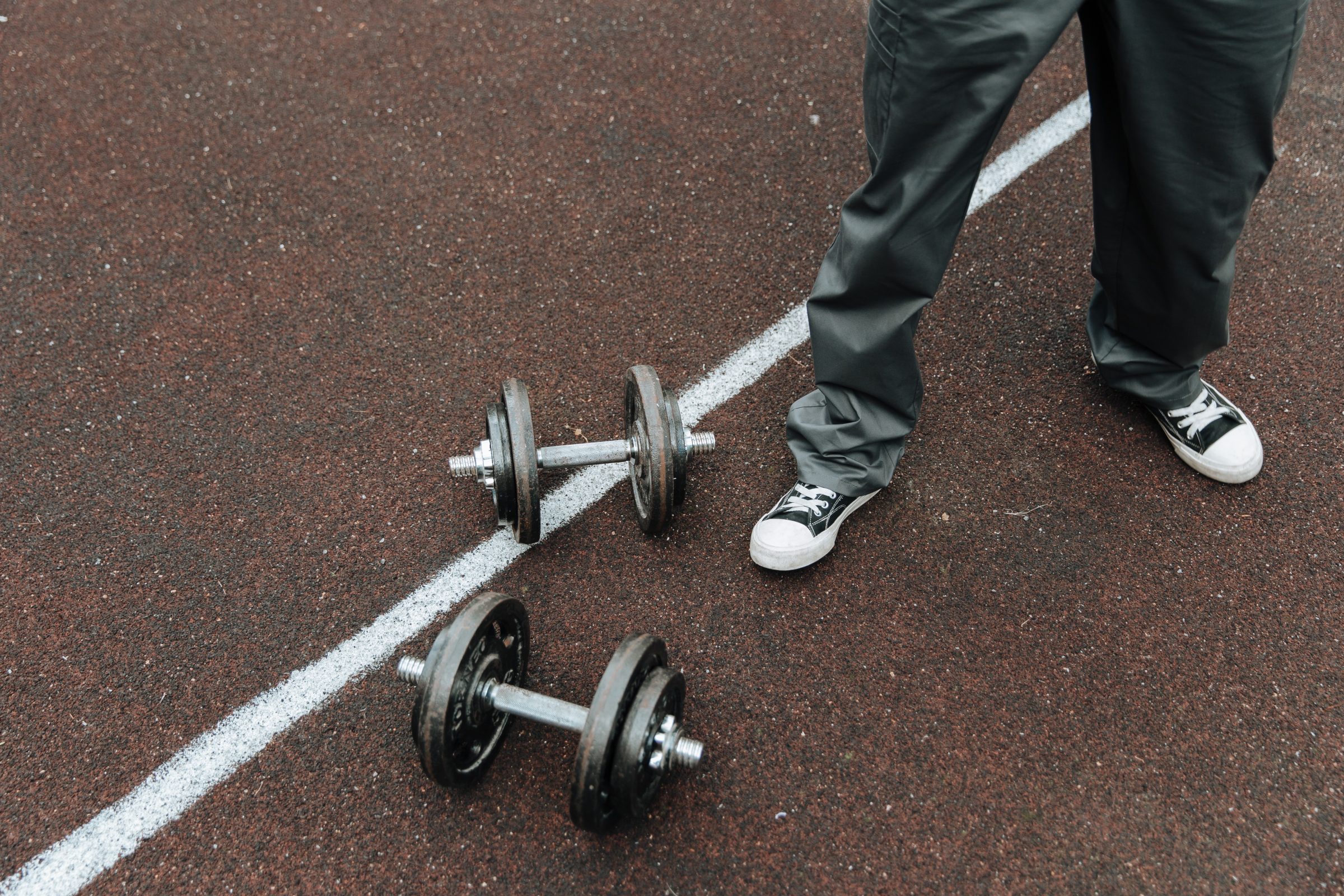 Legs standing near two gym weights. 