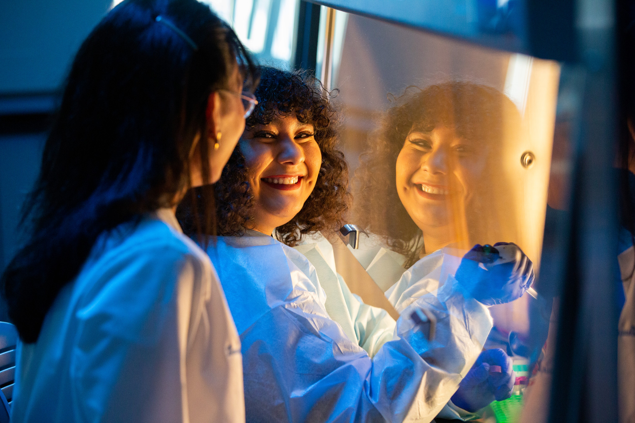 faculty member and student smiling at each other while in the laboratory.