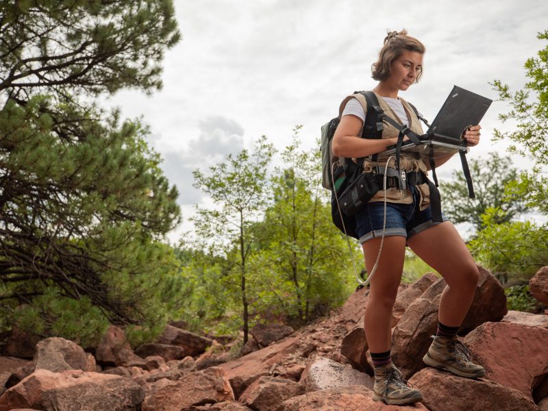 A student holding a computer while outside.