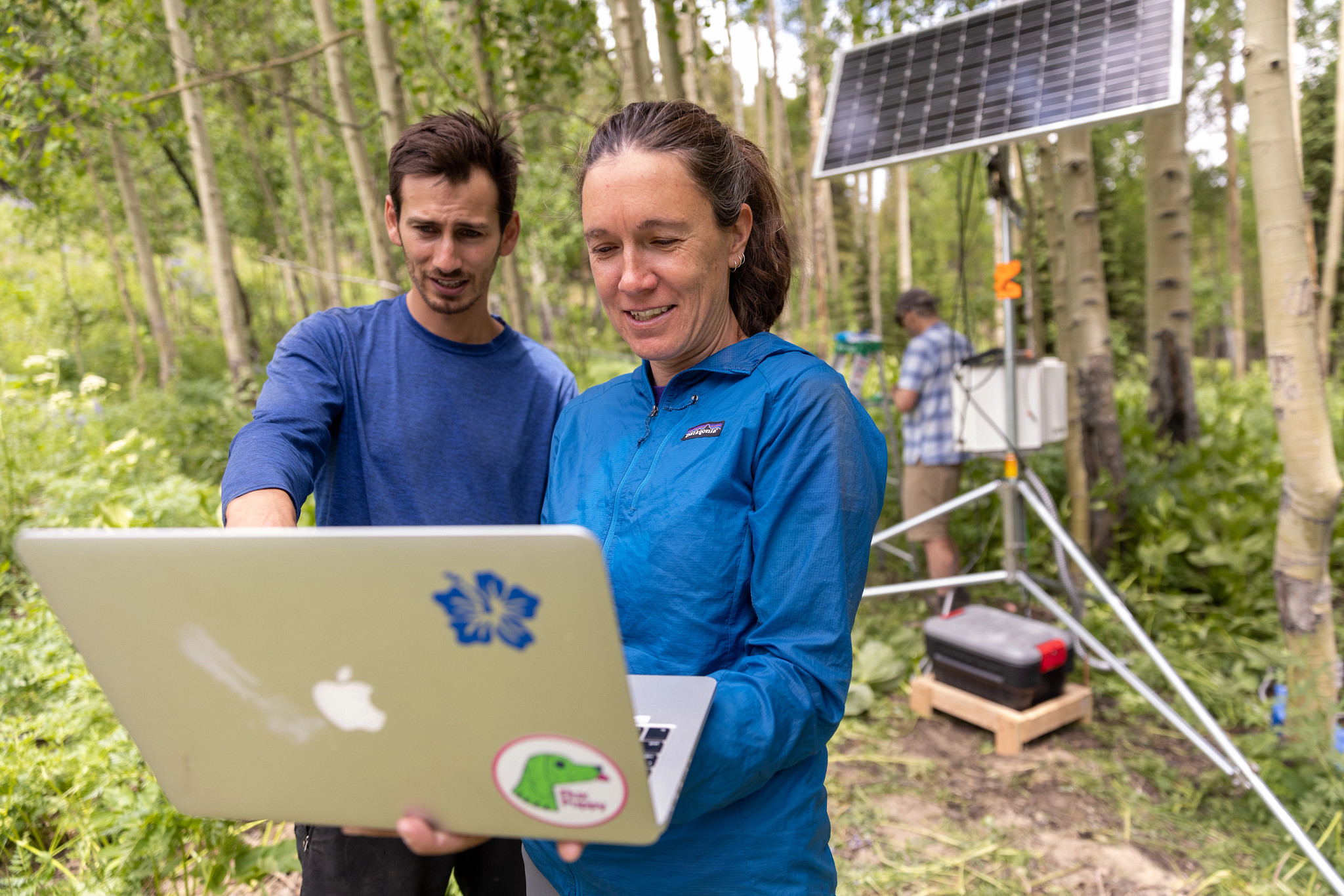 A faculty member working on her computer outside with a student.