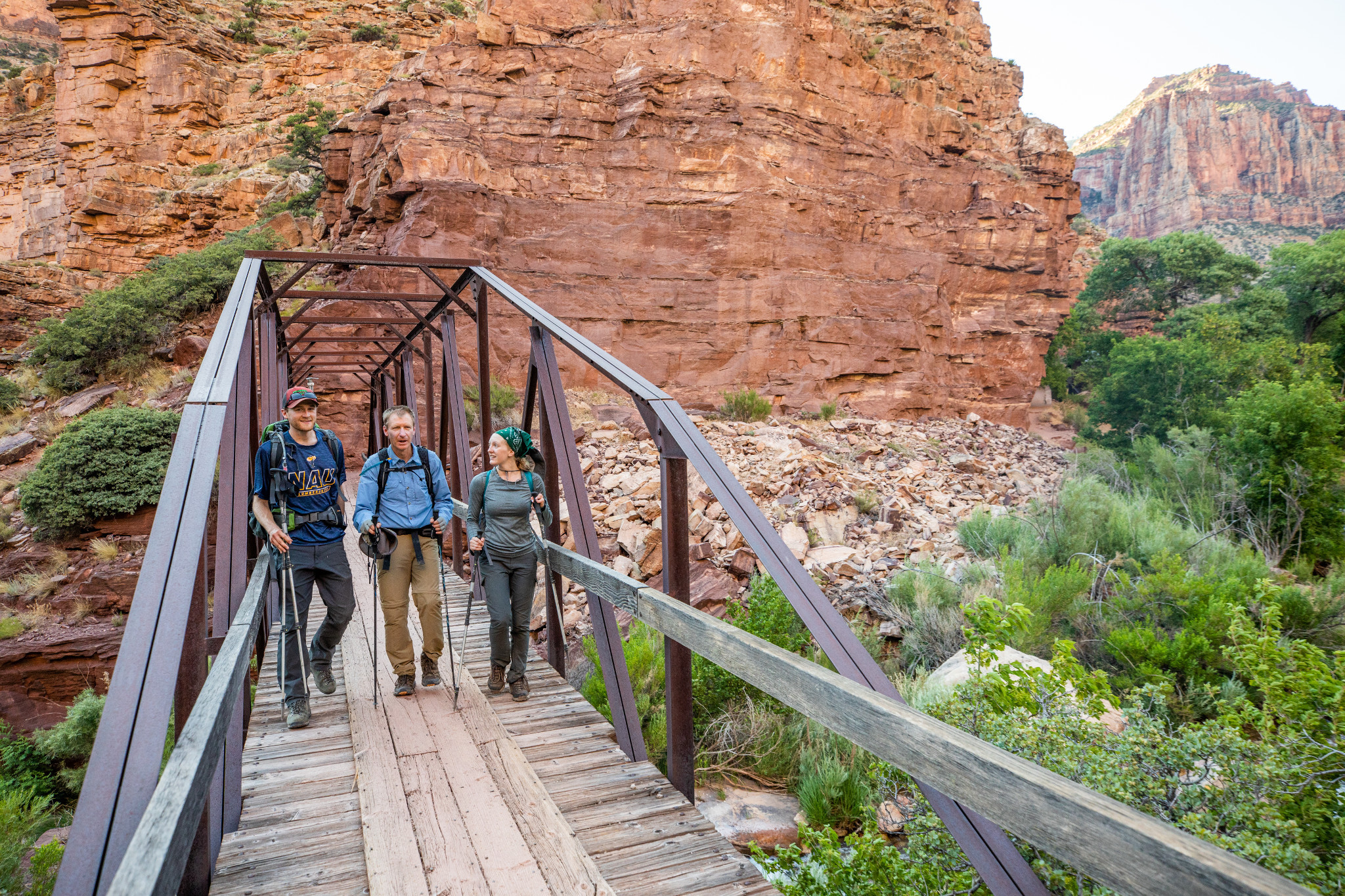 Three people walking through a bridge in the grand canyon.