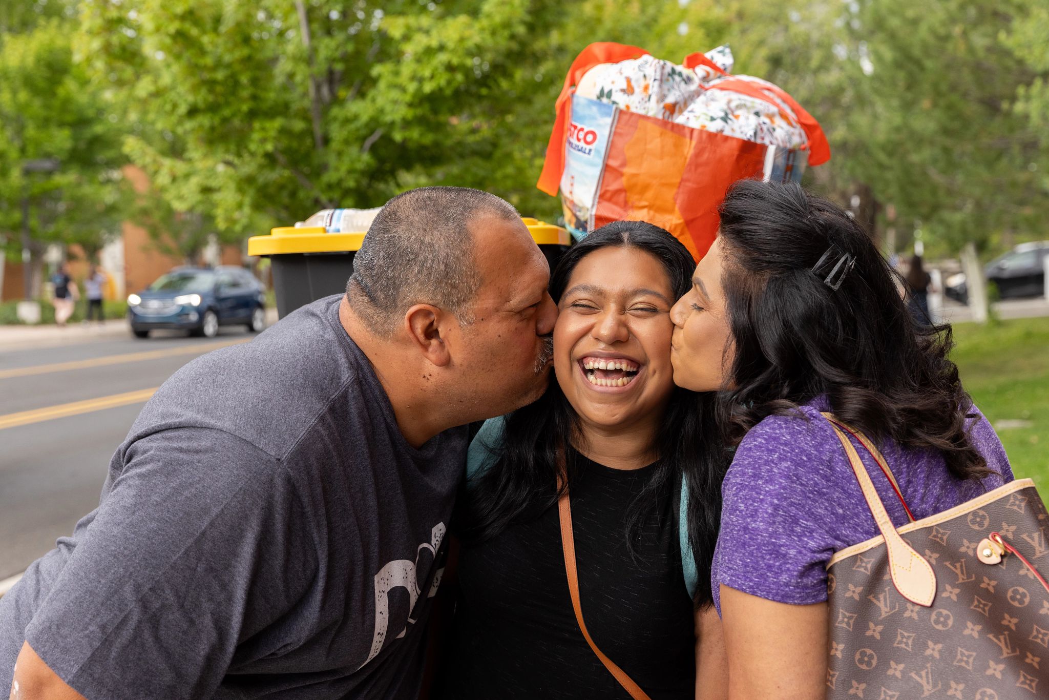 Family on move in day kissing their student on the cheek.