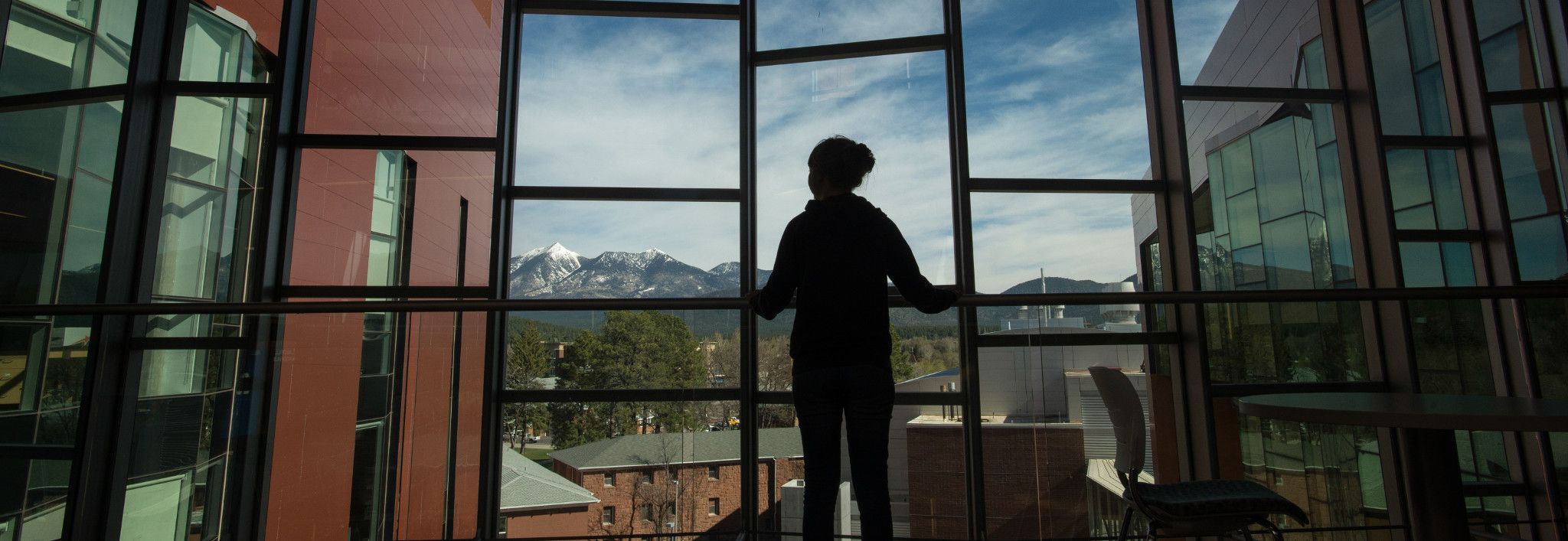 Student looking out the windows of a N A U building.