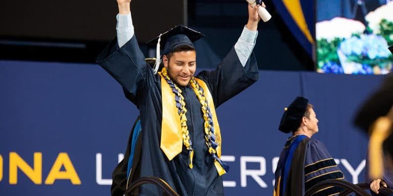 NAU graduation 2023 student with cap and gown and diploma in hand