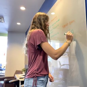 A student is white boarding in the Lumberjack Lounge.