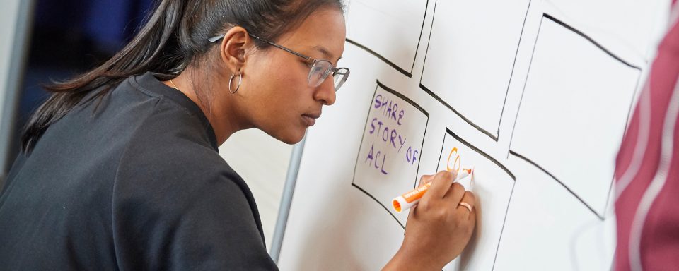 student working on a solution on a whiteboard