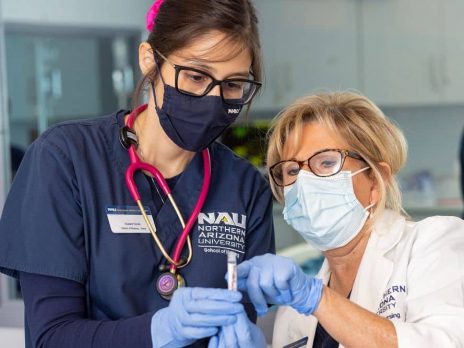 Nursing student and nursing instructor look at a vial
