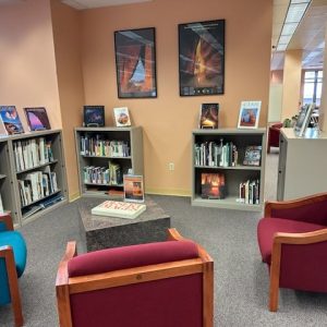 Low bookcases and a small seating area with books on display and two posters of Muench images on the adjoining wall.Seating area