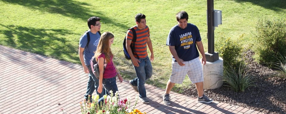 A group of students with backpacks walking down the sidewalk together