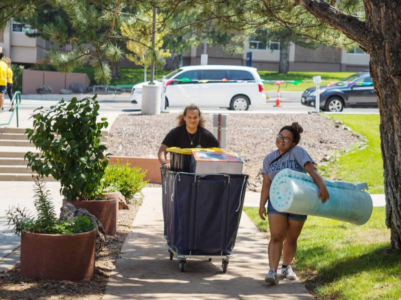 Two students pushing a blue bin moving in.