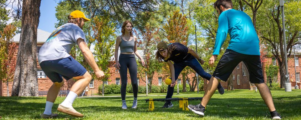 Four students playing spike ball on the north quad lawn