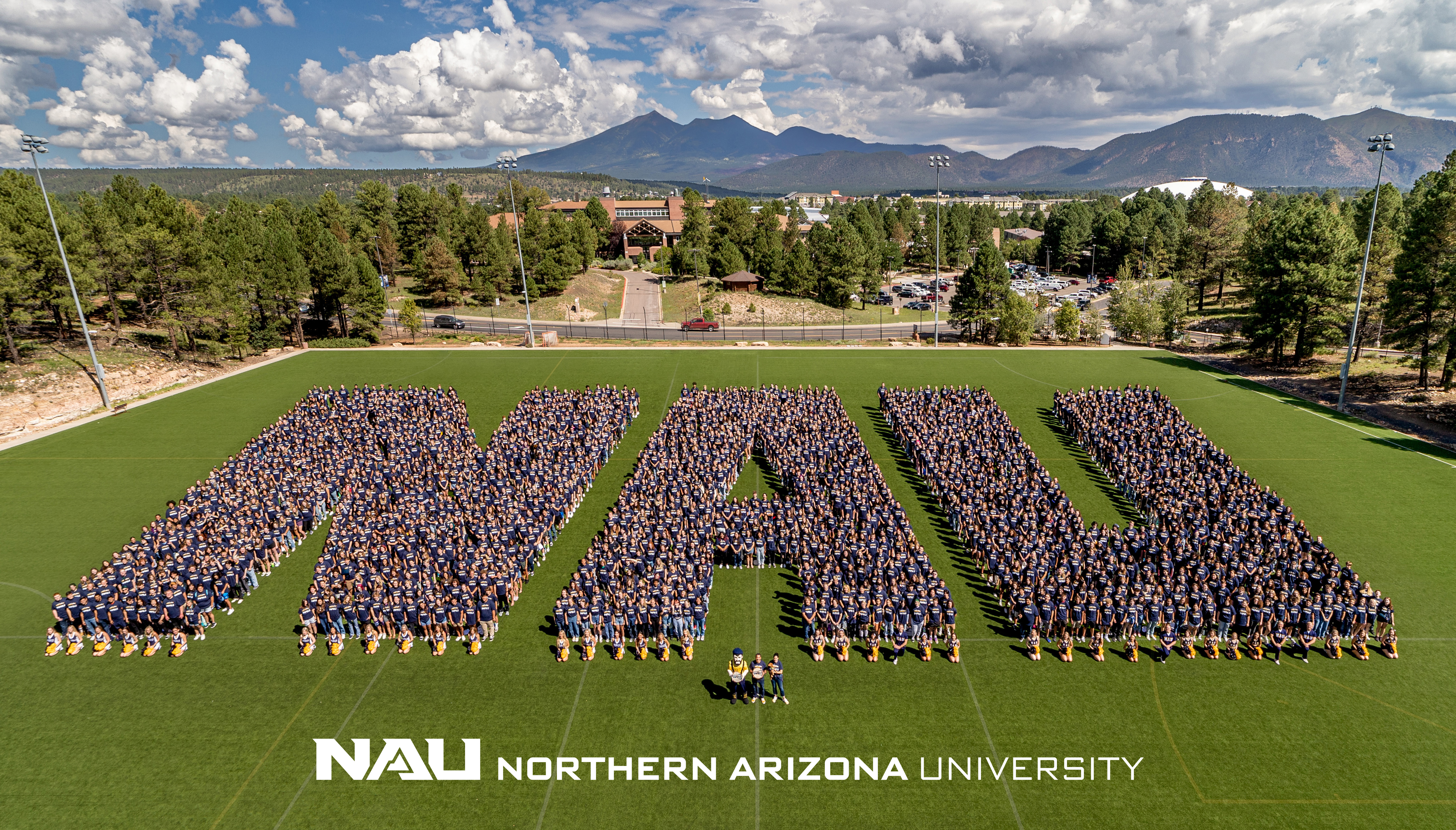 Thousands of students standing on a football field in the shape of NAU letters.