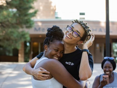 Two students hugging and smiling.
