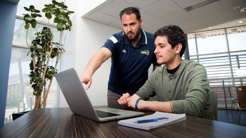 Advisor helping a student on a laptop.