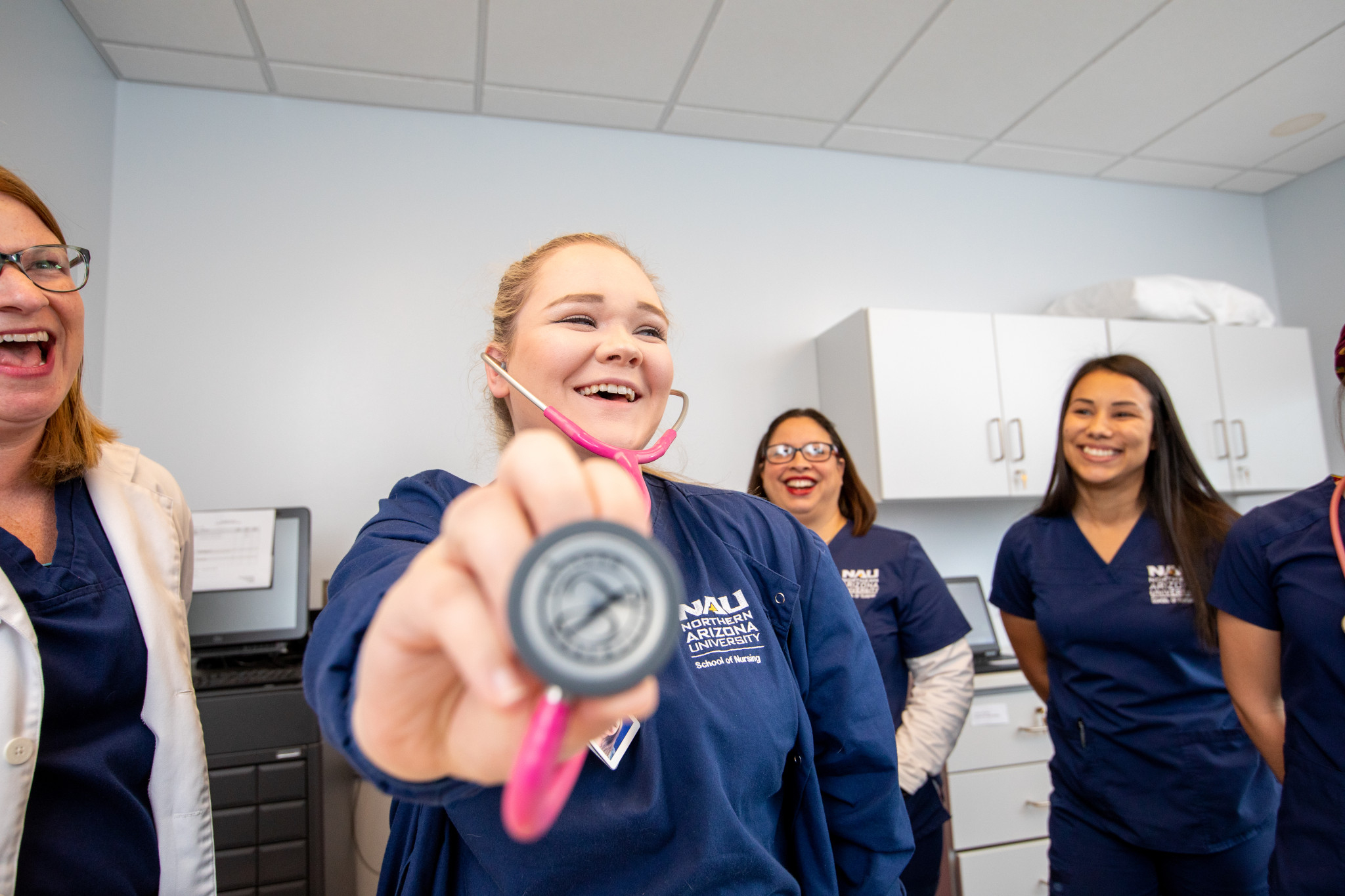 Students smile as they pose with a stethoscope.