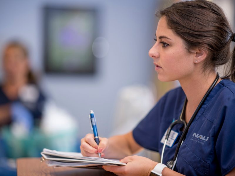 A student in the N A U nursing program takes notes in class.