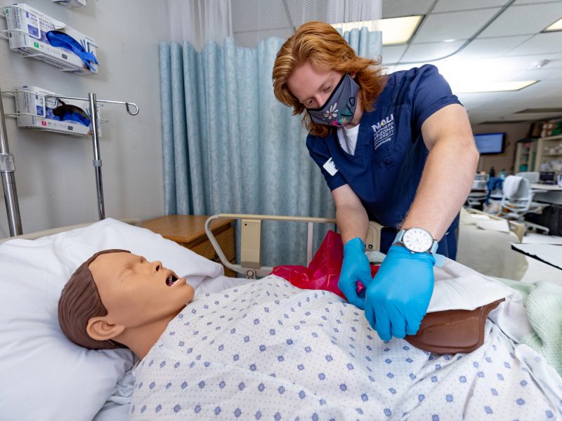 A student in N A U's nursing program practices on a mannequin.